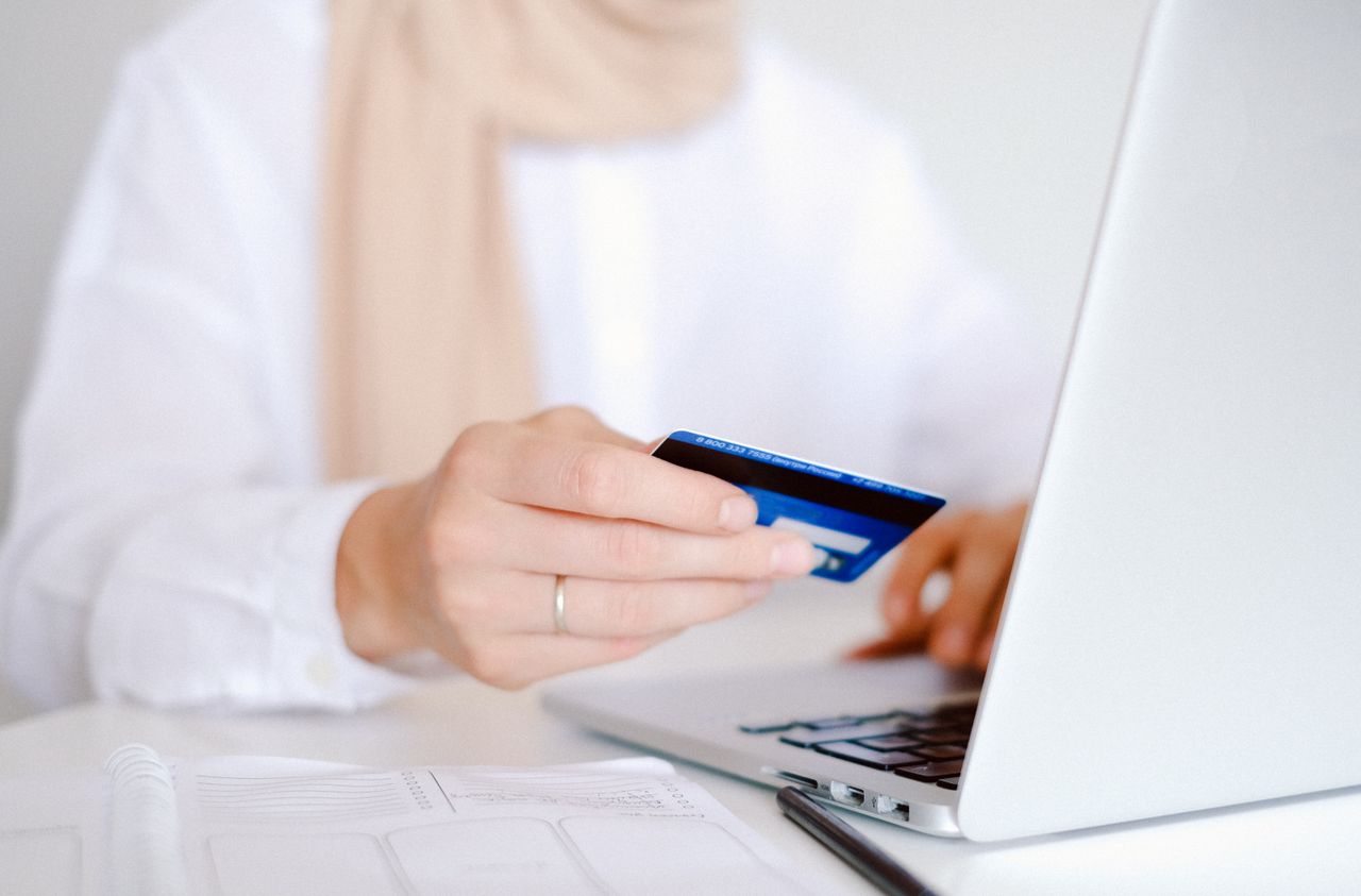The Art of Drawing Readers In: Your attractive post title goes here Close-up of a person holding a credit card while using a laptop for online shopping.